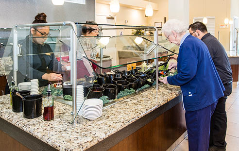 A woman in a blue shirt is reaching for a plate. Description generated by AI